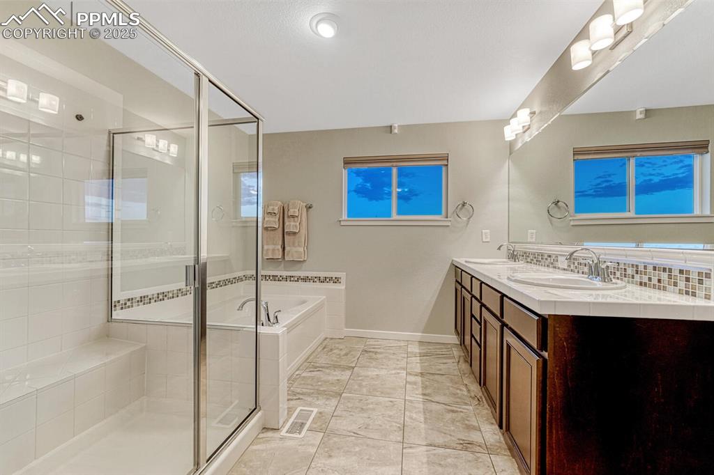 Image 18 of 50: Full bathroom with a garden tub, a stall shower, double vanity, and marble 