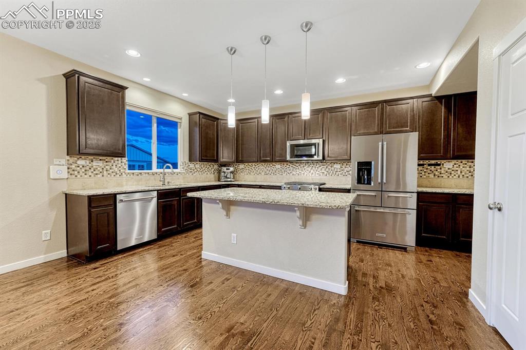 Image 7 of 50: Kitchen with appliances with stainless steel finishes, dark brown cabinetry