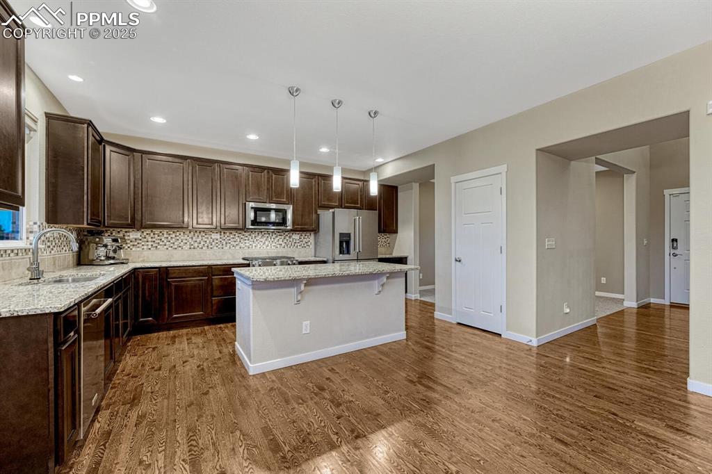 Image 8 of 50: Kitchen with appliances with stainless steel finishes, dark brown cabinets,