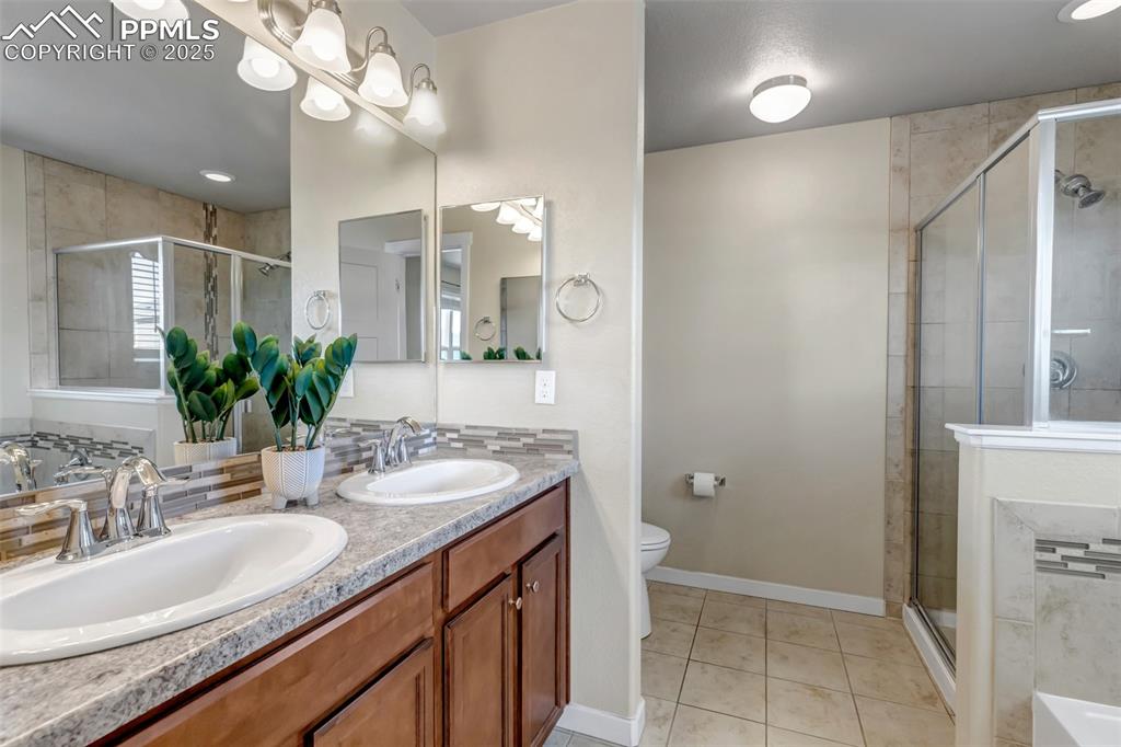 Image 22 of 37: Full bathroom with double vanity, light tile patterned flooring, and a show
