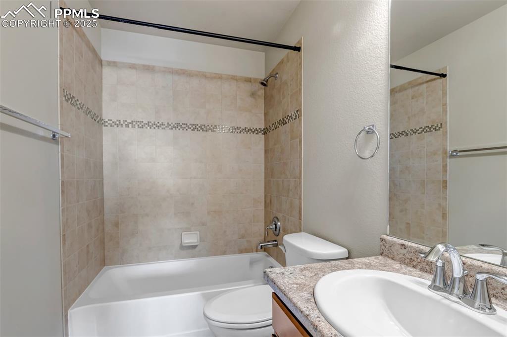 Image 27 of 37: Full bath featuring bathtub / shower combination, vanity, and a textured wa