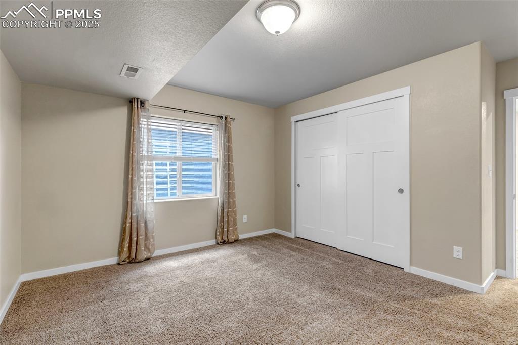 Image 33 of 37: Unfurnished bedroom with light colored carpet, a closet, and a textured cei