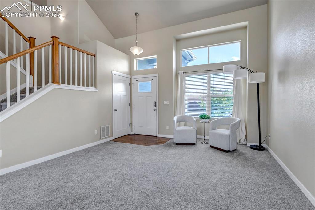 Image 5 of 37: Carpeted entryway with high vaulted ceiling and stairs