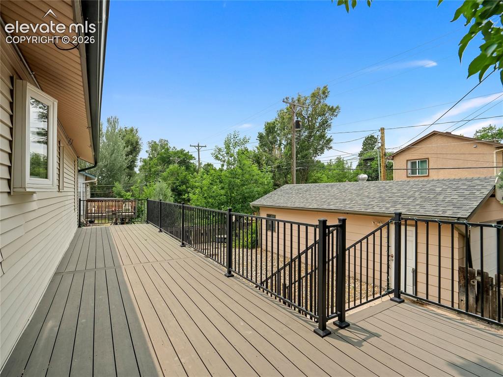 Image 26 of 33: West facing composite deck with iron raining & steps to the backyard