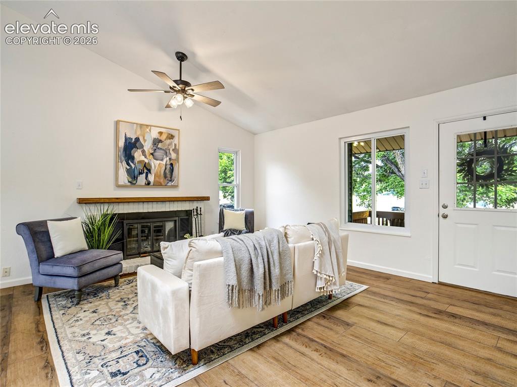 Image 6 of 33: Comfortable gathering space featuring a wood-burning fireplace, ceiling fan