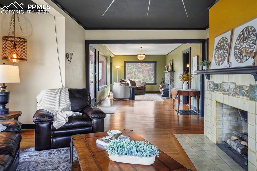 Image 15 of 47: Living area with crown molding, wood finished floors, baseboards, and a til