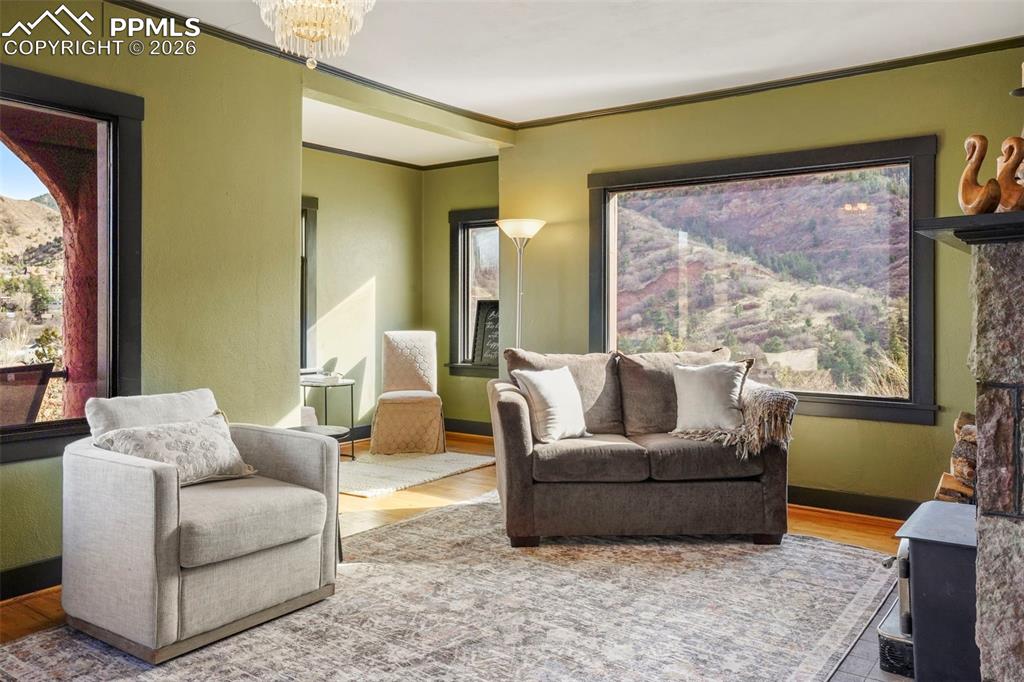Image 19 of 47: Living room with a chandelier, crown molding, wood finished floors, and ple