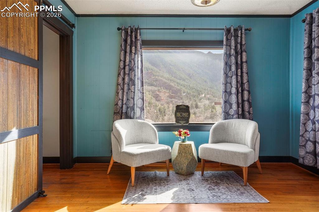 Image 22 of 47: Living area with baseboards, ornamental molding, and wood finished floors a
