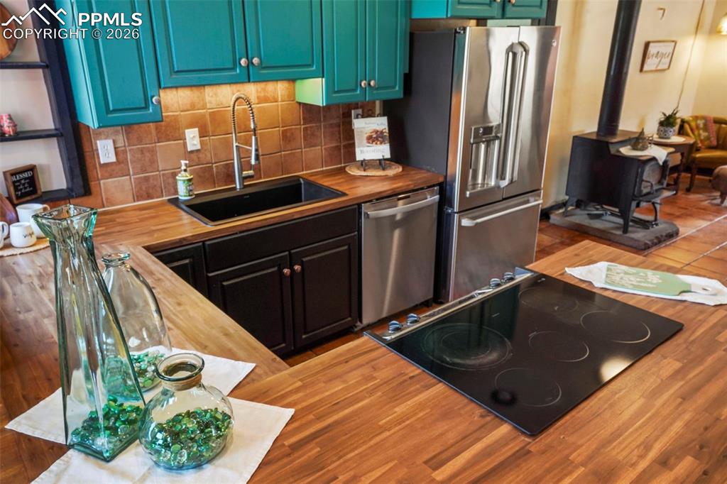 Image 25 of 47: Kitchen featuring new butcher block countertops, decorative backsplash, a s