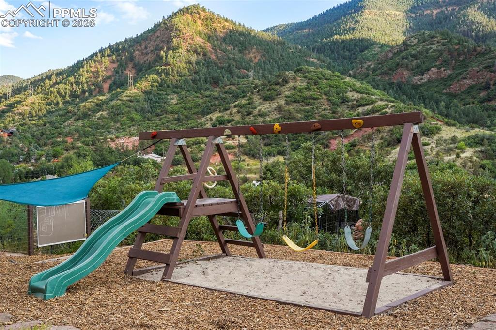 Image 9 of 47: View of jungle gym with a wooded view and a mountain view