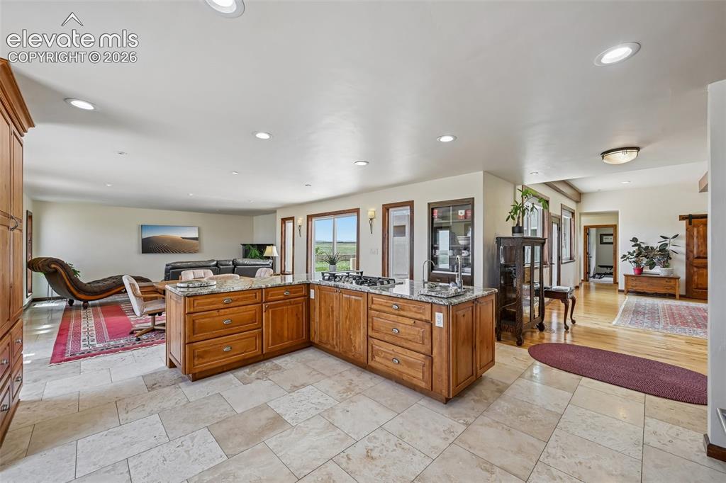 Image 13 of 36: Spacious open-concept kitchen featuring light-toned tile flooring, recessed