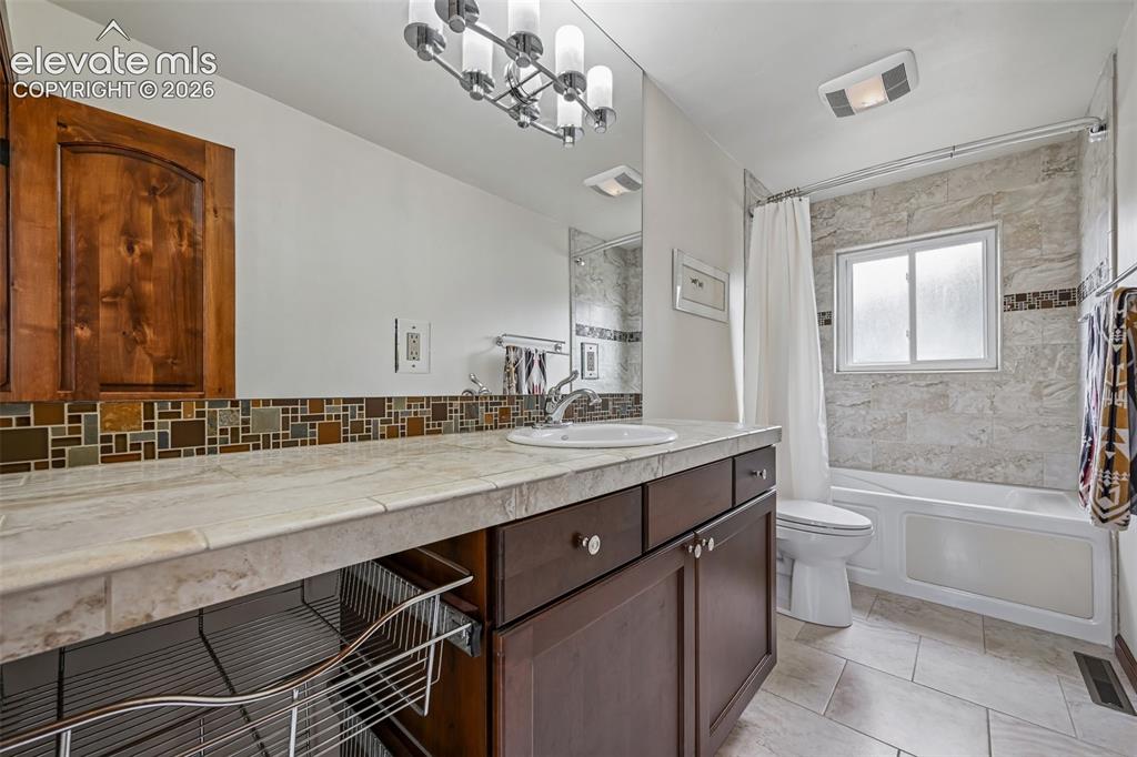 Image 23 of 36: Bathroom featuring a vanity with dark wood-finish cabinetry, a white oval s