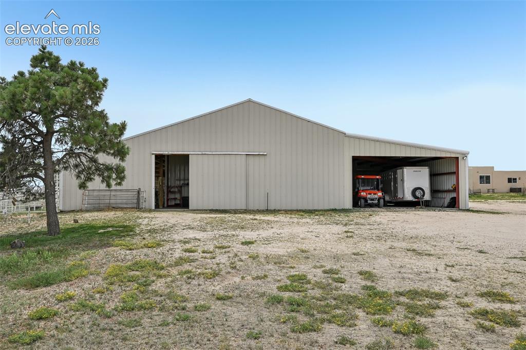 Image 35 of 36: Metal-sided barn structure featuring a large sliding door, an open bay, and