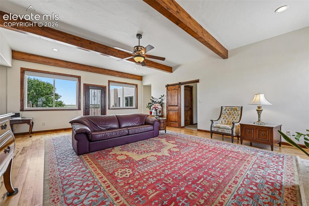 Image 7 of 36: Spacious living area featuring exposed wood beams, vaulted ceilings, wood-f