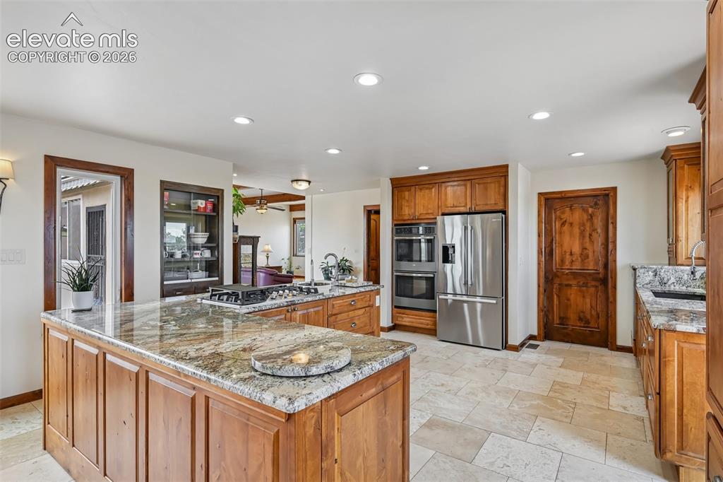 Image 9 of 36: Spacious kitchen featuring custom wood cabinetry, granite countertops, stai