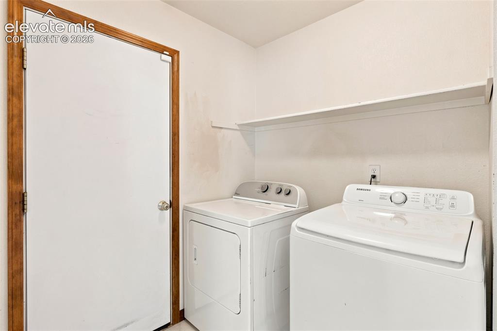 Image 11 of 34: Dedicated laundry area featuring white appliances, a wall-mounted shelving 