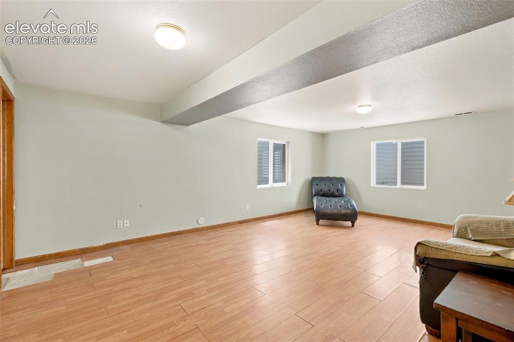 Image 17 of 34: Spacious interior room featuring wood-finish flooring, two large windows, a