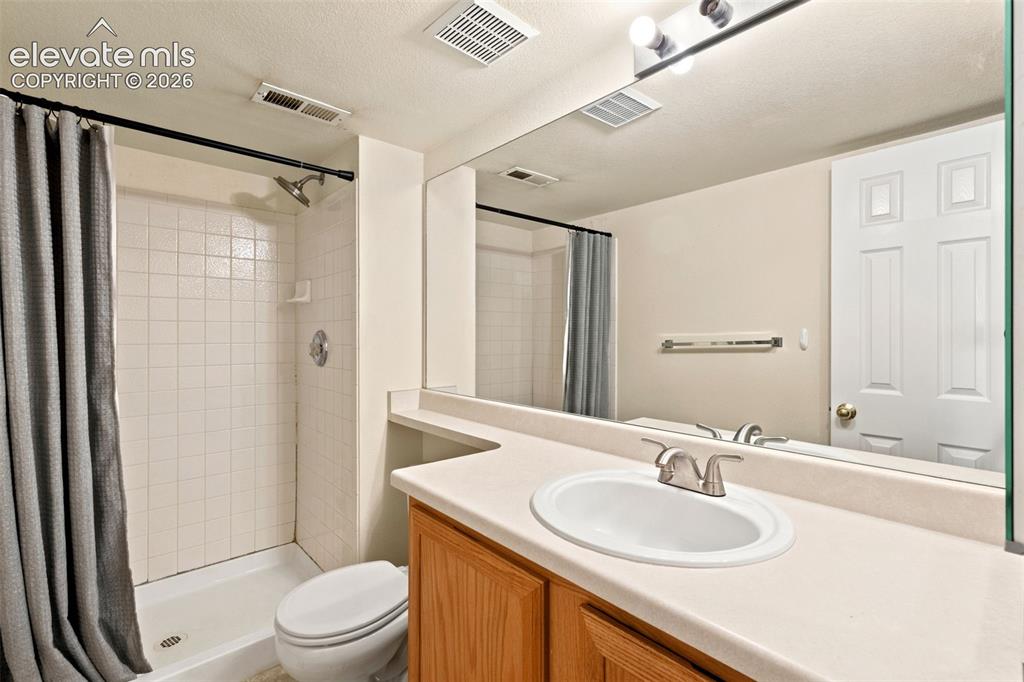 Image 21 of 34: Bathroom featuring a shower with white tile surround, a built-in toilet, a 
