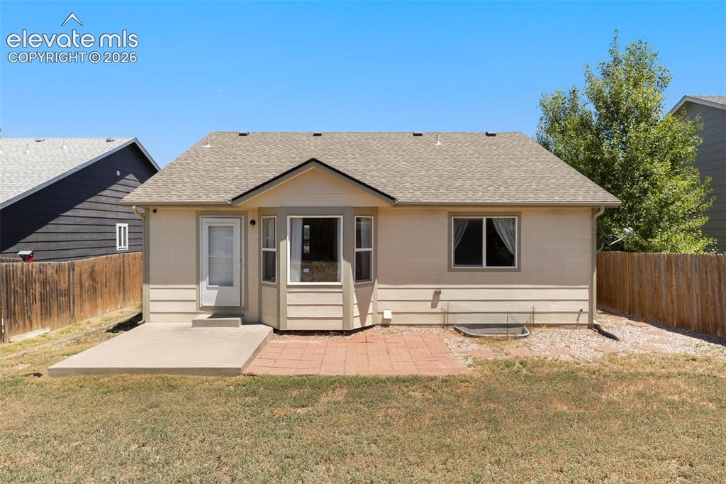 Image 24 of 34: Rear exterior featuring a bay window, concrete patio, and brick paver area