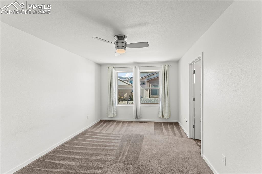 Image 11 of 33: Spare room featuring light colored carpet, ceiling fan, and a textured ceil