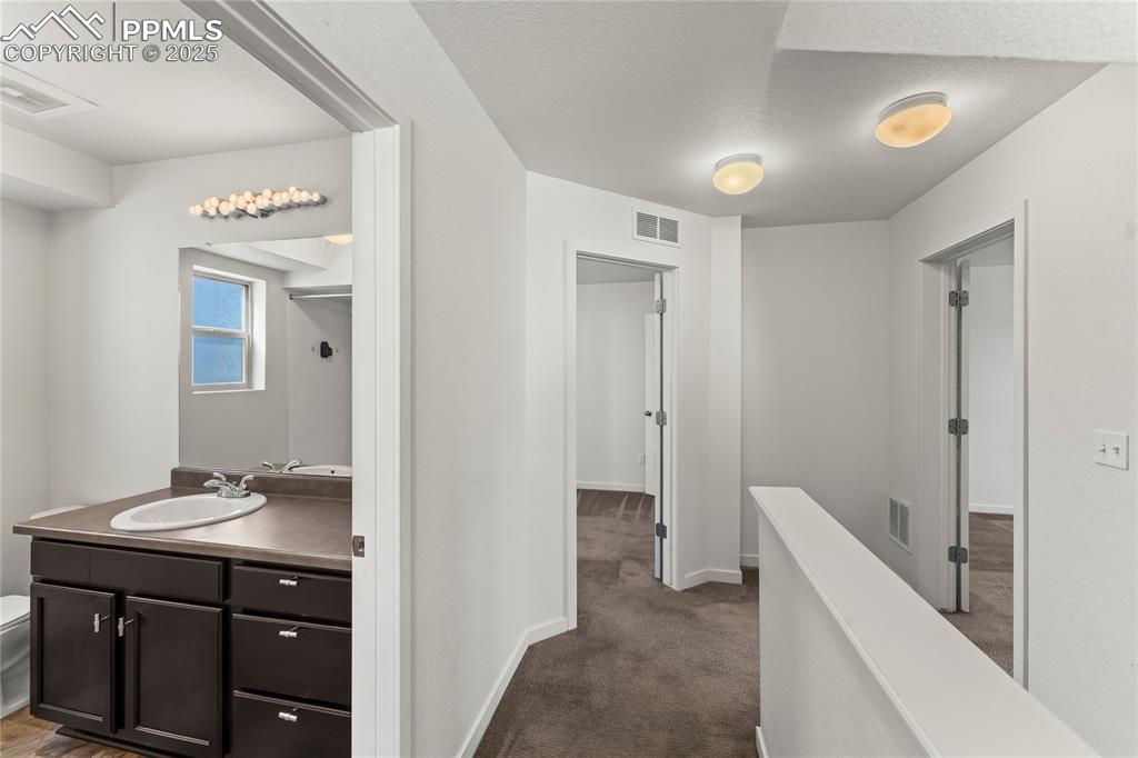 Image 16 of 33: Corridor with dark carpet and a textured ceiling