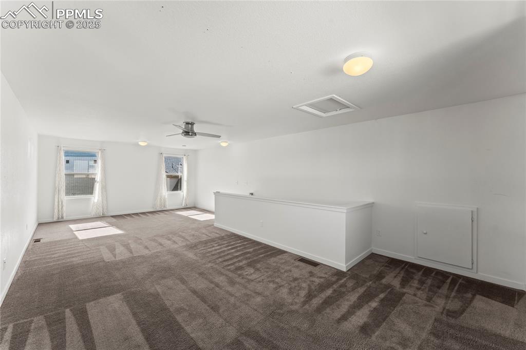 Image 22 of 33: Empty room with dark colored carpet and a ceiling fan