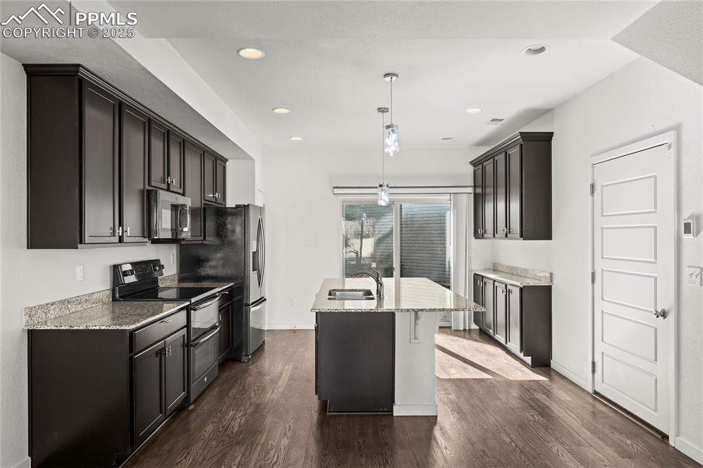 Image 7 of 33: Kitchen with appliances with stainless steel finishes, light stone countert