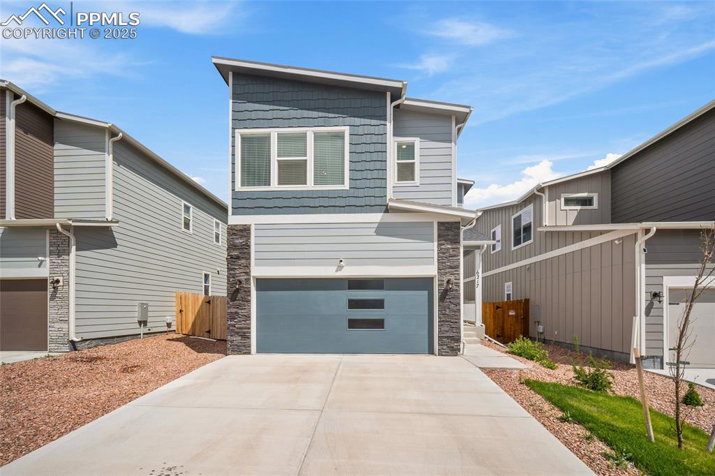 Caption: Modern home featuring stone siding, an attached garage, and concrete driveway