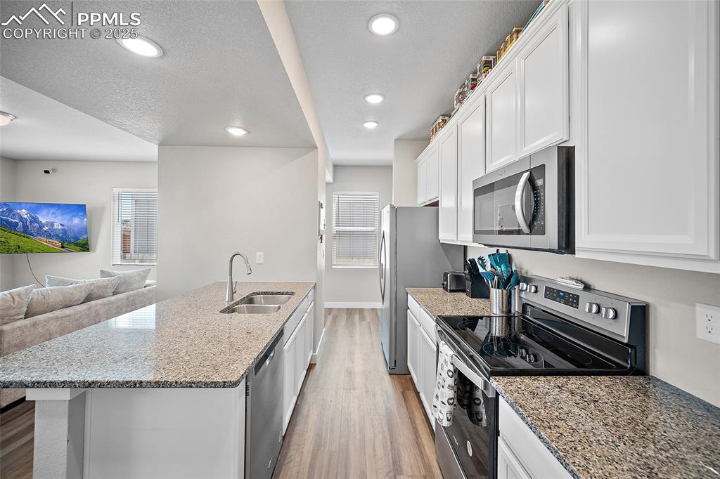 Image 12 of 41: Kitchen featuring stainless steel appliances, a sink, light wood-style floo