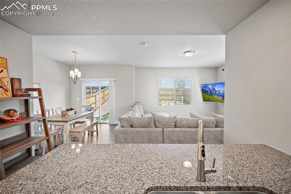Image 13 of 41: Living area with a chandelier, wood finished floors, and a textured ceiling