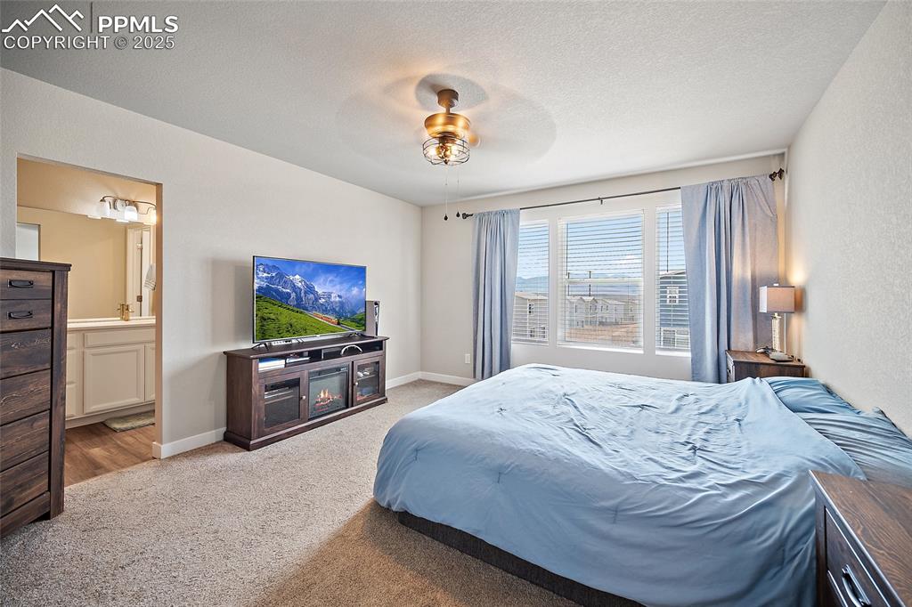 Image 19 of 41: Bedroom with light colored carpet, ensuite bathroom, a textured ceiling, a