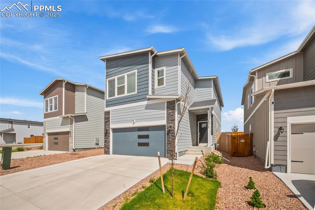 Image 2 of 41: Contemporary home with a garage, concrete driveway, and stone siding