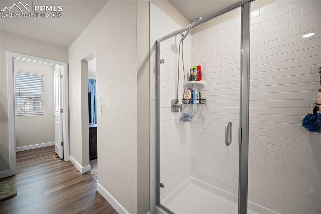Image 27 of 41: Bathroom with wood finished floors, a stall shower, and baseboards