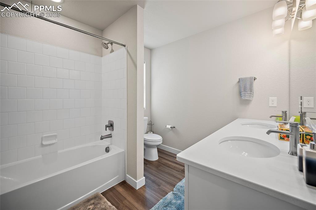 Image 31 of 41: Full bathroom with toilet, wood finished floors, washtub / shower combinati