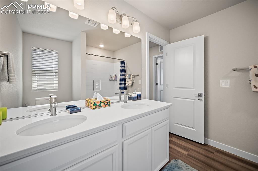Image 32 of 41: Bathroom featuring tiled shower, baseboards, wood finished floors, and doub