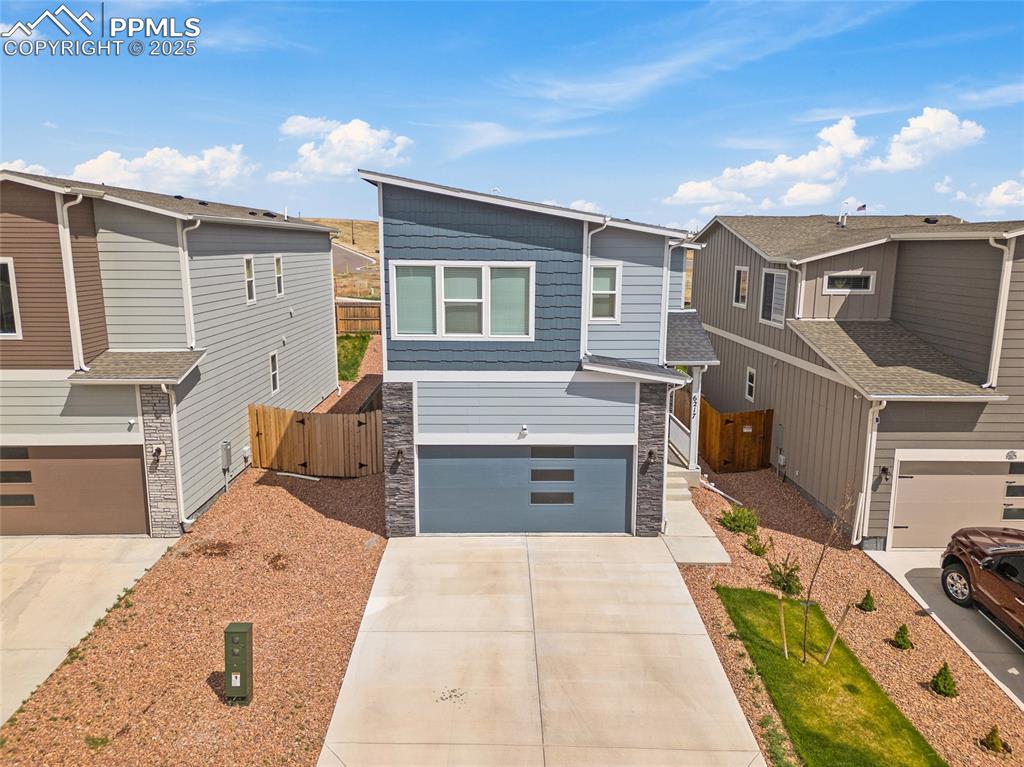 Image 37 of 41: Contemporary home featuring an attached garage, concrete driveway, stone si