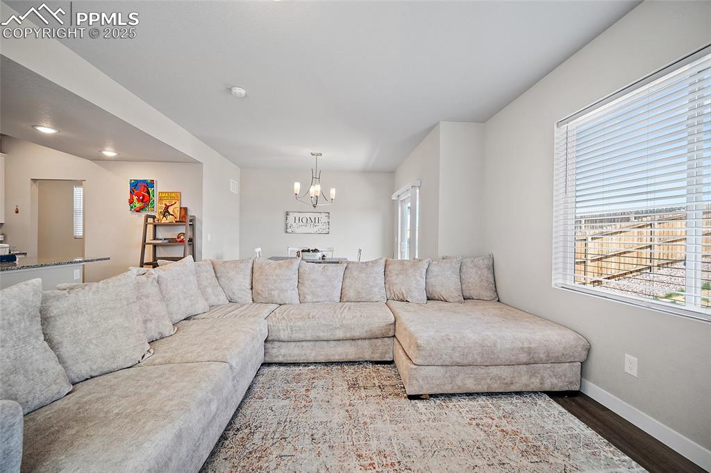 Image 7 of 41: Living area with wood finished floors, a chandelier, and baseboards
