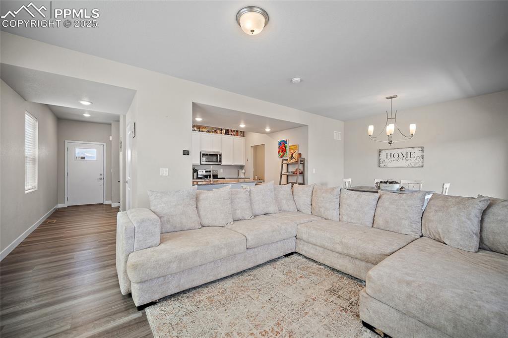 Image 8 of 41: Living room with a chandelier, wood finished floors, baseboards, and recess