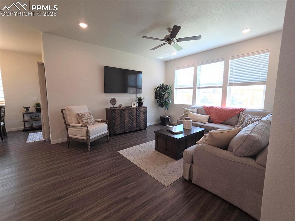 Image 11 of 42: Living area featuring dark wood-style flooring, a ceiling fan, and recessed