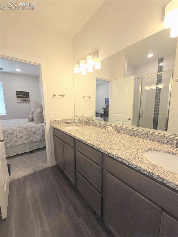 Image 16 of 42: Ensuite bathroom featuring wood finished floors, a shower stall, and double