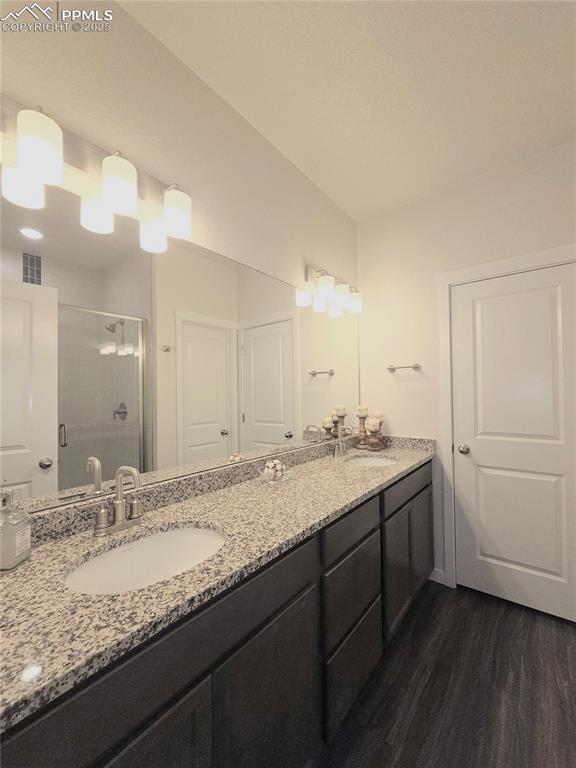 Image 18 of 42: Full bath with wood finished floors, a stall shower, and double vanity