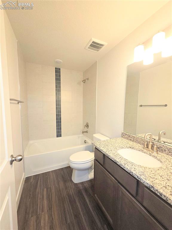 Image 31 of 42: Bathroom with wood finished floors, vanity, and tub / shower combination