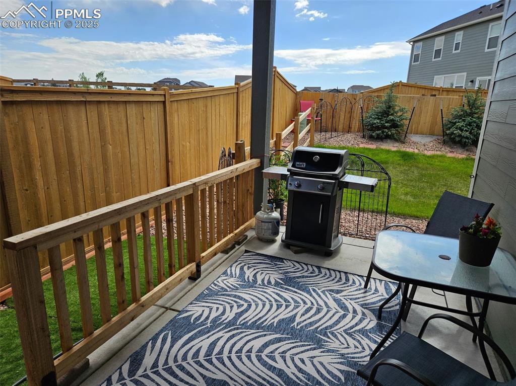 Image 35 of 42: Fenced backyard with area for grilling and a patio