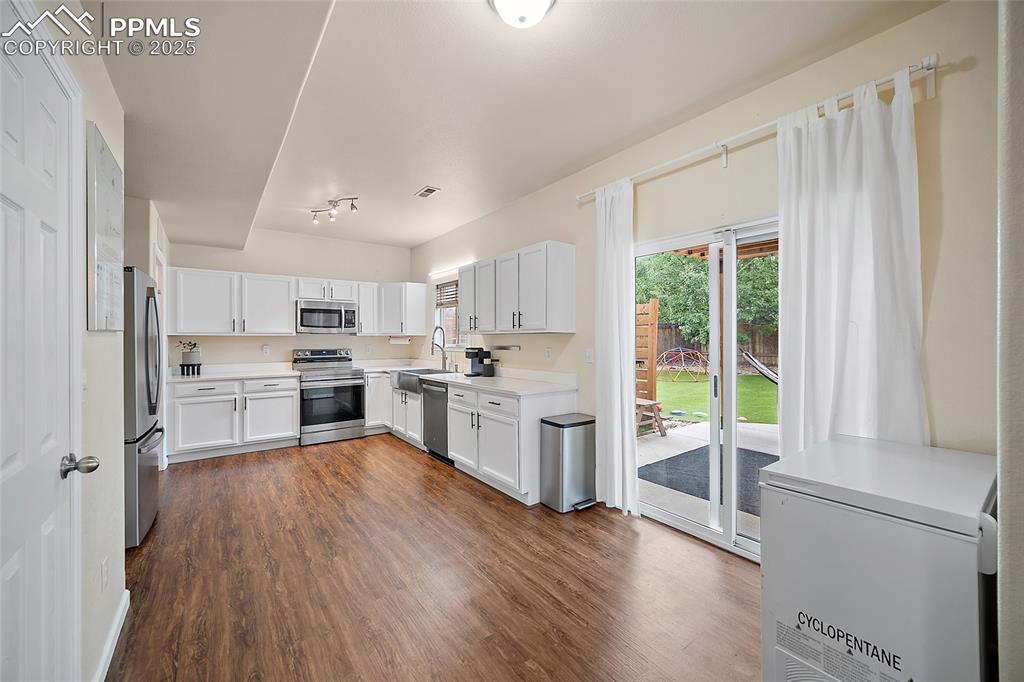 Image 10 of 50: Kitchen featuring light countertops, white cabinets, dark wood finished flo