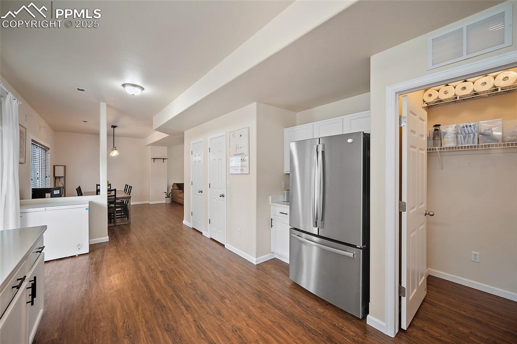 Image 13 of 50: Kitchen featuring freestanding refrigerator, white cabinets, dark wood fini