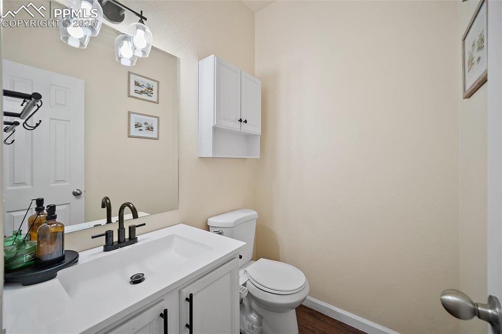 Image 16 of 50: Half bathroom with vanity and dark wood-style floors
