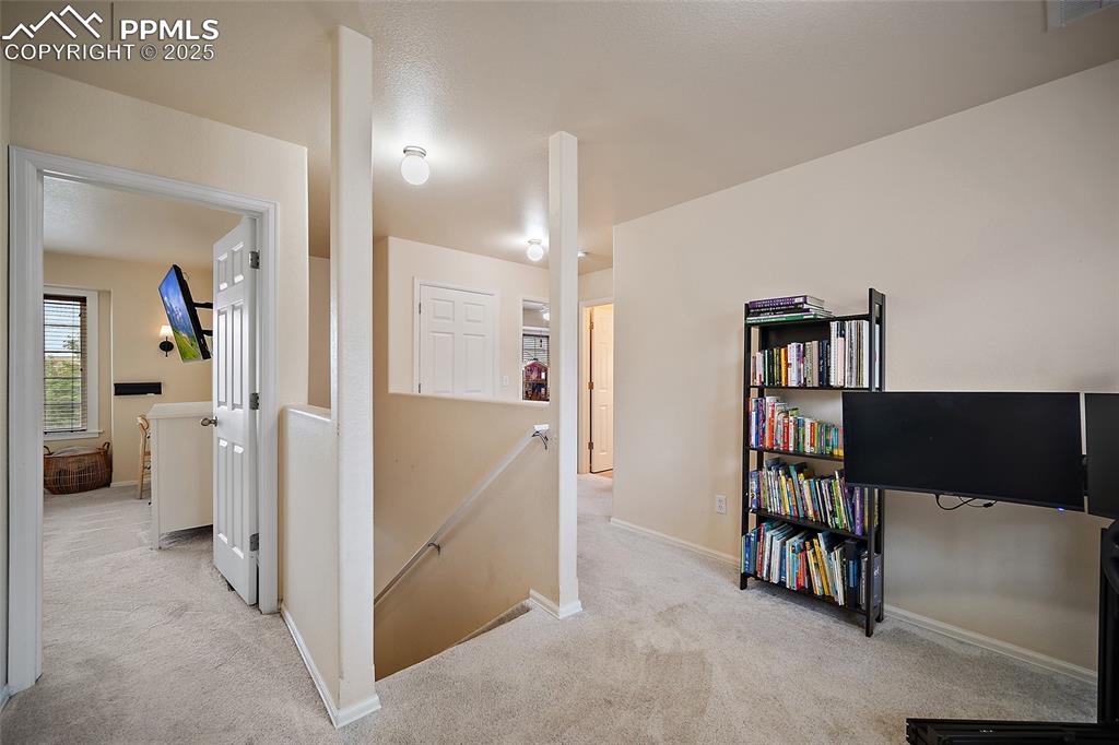 Image 19 of 50: Hallway featuring an upstairs landing and light carpet