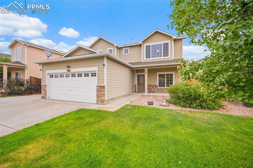 Image 2 of 50: View of front of property featuring stone siding, a front lawn, concrete dr