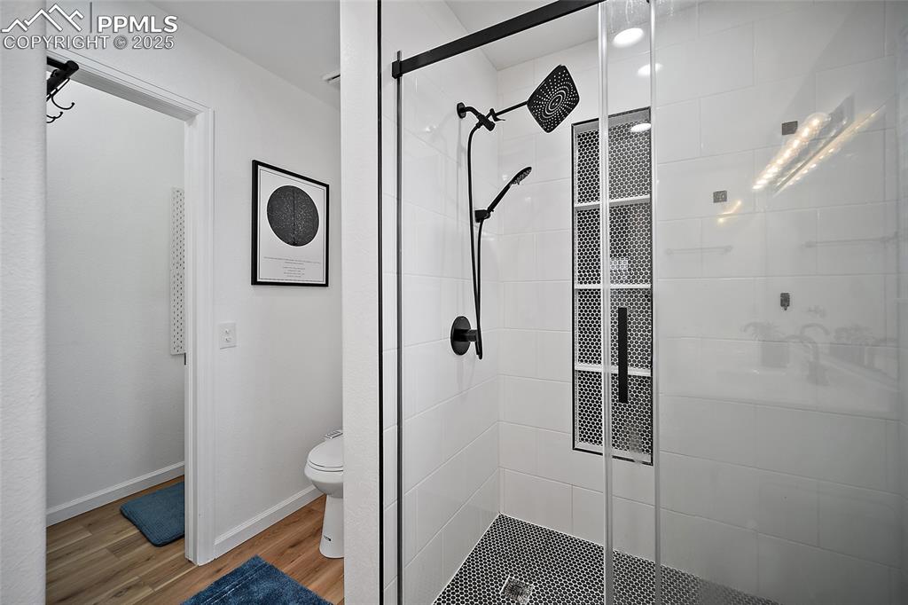 Image 26 of 50: Bathroom featuring a stall shower and light wood-style floors