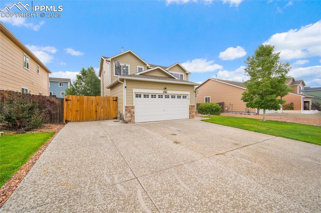 Image 3 of 50: View of front of home featuring driveway, stone siding, a gate, and an atta
